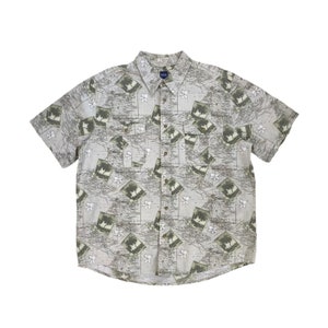 May include: A short-sleeved button-down shirt with a beige background and a repeating pattern of palm trees and a map-like design.