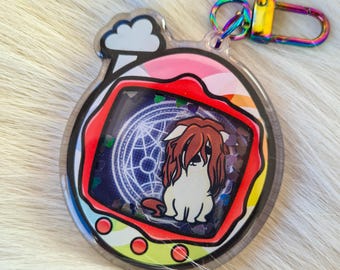 May include: A clear acrylic keychain with a colorful design. The keychain features a cartoon dog inside a red, pink, and yellow frame. The keychain has a rainbow-colored clasp and a cloud design at the top.