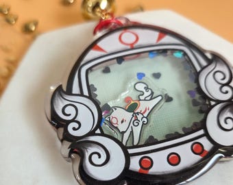 May include: A clear acrylic charm featuring a cartoon cat design within a cloud-shaped frame. The charm has a shaker element with heart-shaped confetti. The frame is white with black and red accents, and a gold bell hangs from the top.