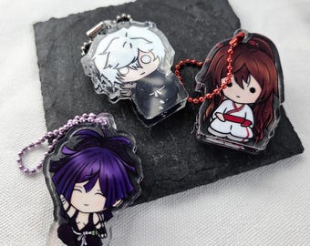 May include: Three acrylic keychains featuring chibi-style anime characters. One has white hair and a black outfit, one has long reddish-brown hair in a white and red outfit with a red chain, and one has purple hair in a black outfit with a purple chain.