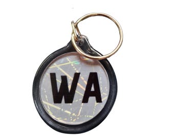 May include: Black and gold key chain with a round, clear, iridescent charm that says "WA" in black letters.