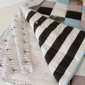 May include: A patchwork quilt with a variety of fabrics, including black and white stripes, blue and white gingham, and a geometric pattern. The quilt is folded in half, revealing the different fabrics.
