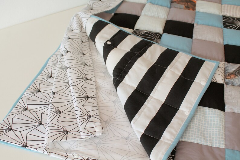 May include: A patchwork quilt with a variety of fabrics, including black and white stripes, blue and white gingham, and a geometric pattern. The quilt is folded in half, revealing the different fabrics.
