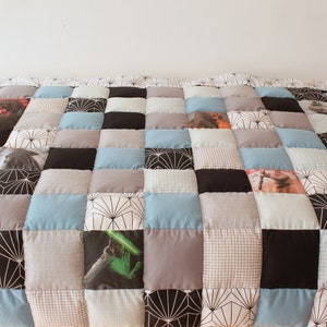 May include: A patchwork quilt with a variety of patterns and colors, including black, white, gray, blue, and brown. The quilt is made up of squares, and some of the squares have images printed on them.