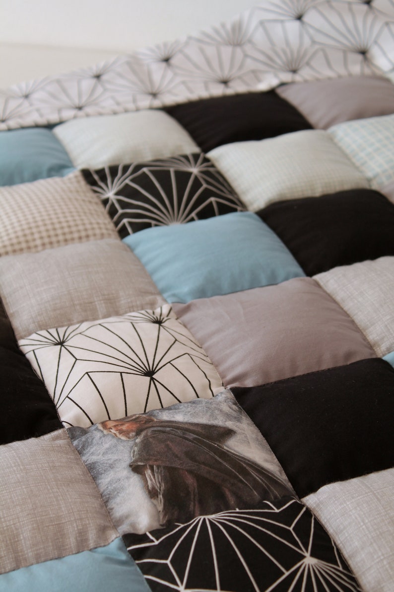 May include: A patchwork quilt with various patterns and colors, including black, white, gray, and blue. The quilt is made of squares and rectangles, and some of the squares have geometric designs.