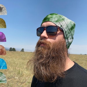 May include: A person wearing a green and white tie-dye beanie with a long brown beard. The beanie is made of a soft, stretchy fabric and is ideal for keeping your head warm in the winter.