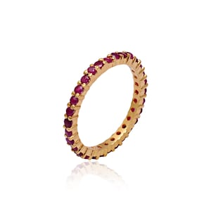 May include: A gold band ring with a row of small, round, red gemstones.