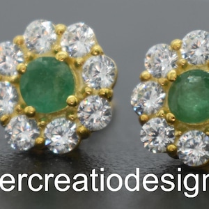 May include: A pair of gold earrings with a green emerald gemstone surrounded by small clear cubic zirconia stones.