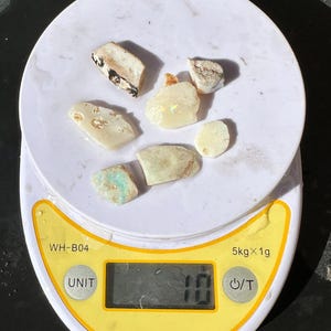 K&ouml;nnte beinhalten: Eine digitale Waage mit wei&szlig;er Oberfl&auml;che zeigt ein Gewicht von 10 Gramm an. Mehrere unregelm&auml;&szlig;ig geformte, hellfarbige Steine sind auf der Waage angeordnet. Die Waage hat einen gelben Rand und eine schwarze Digitalanzeige.