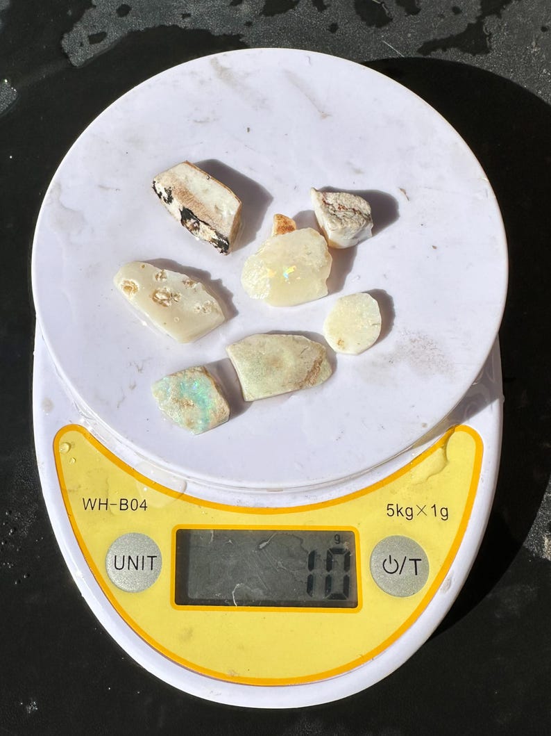 K&ouml;nnte beinhalten: Eine digitale Waage mit wei&szlig;er Oberfl&auml;che zeigt ein Gewicht von 10 Gramm an. Mehrere unregelm&auml;&szlig;ig geformte, hellfarbige Steine sind auf der Waage angeordnet. Die Waage hat einen gelben Rand und eine schwarze Digitalanzeige.