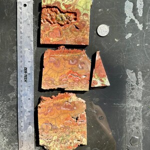 Puede incluir: Cuatro piezas de &aacute;gata pulida con un patr&oacute;n de color rojo, naranja, amarillo y verde. La &aacute;gata est&aacute; cortada en diferentes formas y tama&ntilde;os.