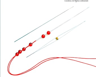 May include: Three beading needles with red beads strung on one of the needles. The needles are silver and the beads are red. A red thread is looped around the needles.