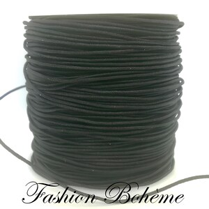May include: A spool of black elastic cord. The cord is tightly wound, showing a textured surface. The words "Fashion Boh&egrave;me" are written in a cursive font at the bottom of the image.