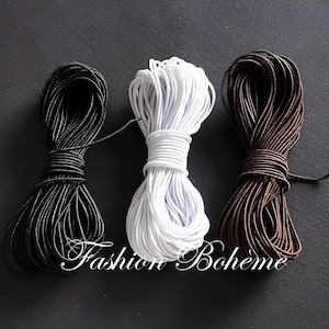 May include: Three bundles of cord in black, white, and brown against a dark background. The cords are tightly wound and appear to be made of a smooth, flexible material. The text "Fashion Boh&egrave;me" is visible.