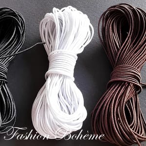 May include: Three spools of cord in black, white, and brown. The cords are tightly wound, with loose ends visible. The image is set against a dark background. The text "Fashion Boh&egrave;me" is in the bottom center.