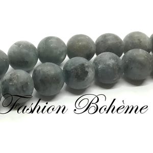 May include: A strand of grey and blue round beads. The beads are smooth and have a slightly mottled appearance.