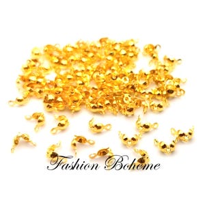 Op de afbeelding: Een grote stapel gouden metalen sluitingen, ook wel bekend als kreeftsluitingen, die worden gebruikt voor het maken van sieraden.