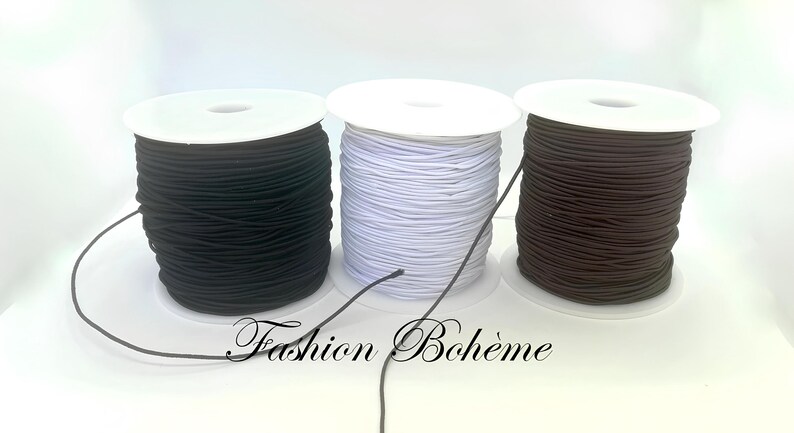 May include: Three spools of elastic cord in black, white, and brown. The spools are on white cardboard bases. The text "Fashion Boh&egrave;me" is at the bottom of the image.