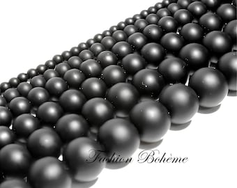 May include: A strand of black matte round beads. The beads are arranged in a diagonal line, creating a visual effect of depth and texture.