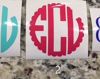 May include: Three white vinyl stickers with different monogram designs. The first sticker has a turquoise circle with white letters "ECU" inside. The second sticker has a pink circle with white letters "ECU" inside and a scalloped edge. The third sticker has a blue cursive monogram "ECS".