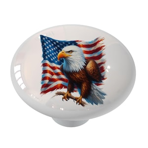May include: A white ceramic knob with a colorful image of a bald eagle perched on a branch with the American flag behind it.