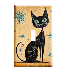May include: A light switch cover featuring a black cat with teal blue eyes and a starry pattern. The cat is sitting on a light yellow background with teal blue stars.