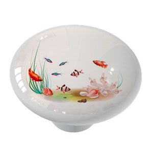 May include: A white ceramic knob with a colorful underwater scene. The scene features red and orange fish, coral, and green seaweed.