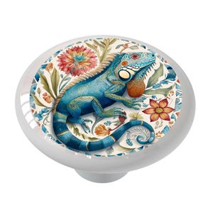 May include: A ceramic knob with a blue iguana on a white background with colorful floral designs.