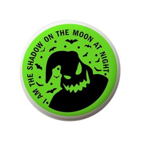 May include: A green circle with a white border and the text "I am the shadow on the moon at night."  The text is in black and there is a black silhouette of a creature with a large grin.