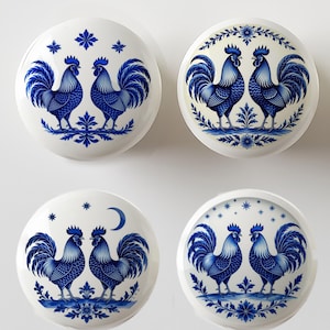 May include: Four white ceramic cabinet knobs with blue rooster designs. Each knob features a pair of roosters with detailed blue feathers and floral accents. The knobs are round and have a glossy finish, perfect for adding a touch of farmhouse charm.