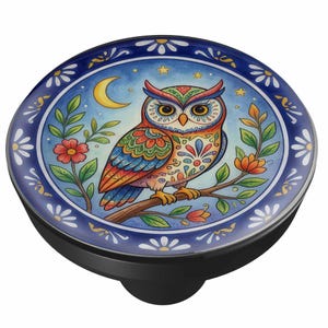 May include: A round phone grip featuring a colorful owl illustration perched on a branch against a night sky with a crescent moon and stars. The design is framed by a dark blue border with white daisy-like flowers and has a black base.