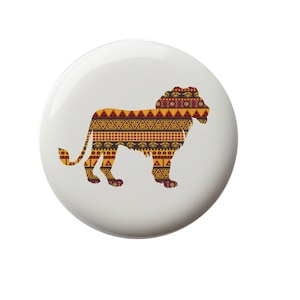 May include: A white button with a silhouette of a lion in a geometric pattern of red, yellow, and brown. The lion is facing right.
