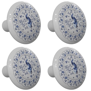 May include: Set of four white ceramic cabinet knobs with a blue and white peacock design. Each knob features a peacock with a blue tail and a white body, surrounded by a blue and white floral pattern.