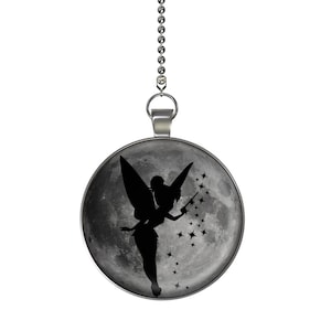 May include: A silver chain with a round pendant featuring a black silhouette of a fairy with wings and a wand, flying over a gray moon with white stars.
