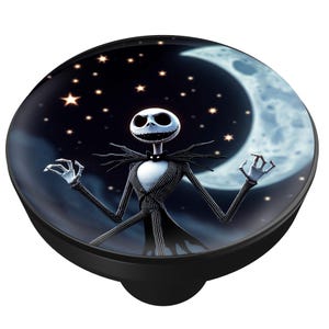 May include: Black cabinet knob featuring Jack Skellington from The Nightmare Before Christmas. The image shows Jack with a white face, black pinstripe suit, and a night sky background with a crescent moon and stars.