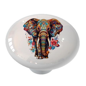 May include: A white ceramic knob with a colorful illustration of an elephant with floral accents. The elephant is decorated with intricate patterns and vibrant colors.