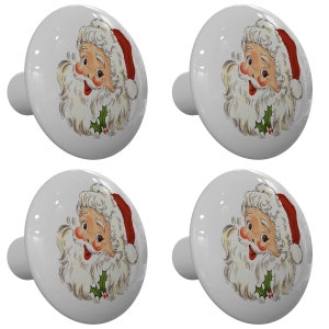 May include: Set of four white ceramic cabinet knobs with a vintage illustration of Santa Claus's face. Each knob has a red and white Santa hat, a white beard, and a holly sprig.