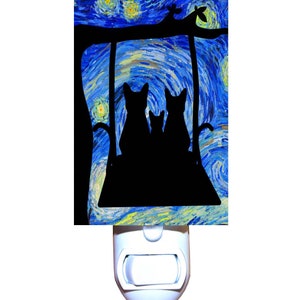 May include: A nightlight featuring a silhouette of three cats sitting on a swing against a blue and yellow starry night background.