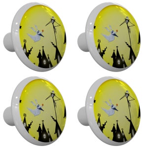 May include: Set of four ceramic cabinet knobs featuring a yellow moon with a black silhouette of a spooky town and a character from the Nightmare Before Christmas movie. The character is standing on a rooftop with a dog flying in the air.