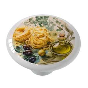 May include: A white ceramic knob with a design of pasta, olives, and olive oil on a green and brown background.