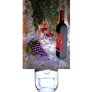 May include: A nightlight featuring a still life of a bottle of red wine, two wine glasses, and a bunch of purple grapes. The bottle has a red label with the text "Mili" and "Bordeaux 2001".