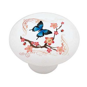May include: A white ceramic knob with a blue butterfly on a branch with pink flowers and gold accents.