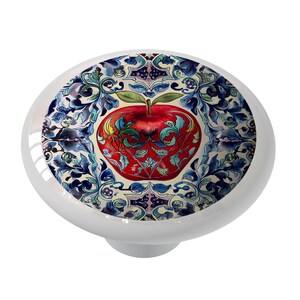 May include: A red apple with a blue and white floral design. The apple is surrounded by intricate floral patterns in shades of blue, white, and green. The background is a cream color.