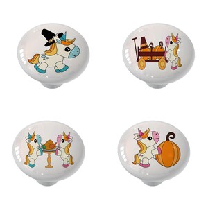 May include: Four white ceramic cabinet knobs with colorful unicorn designs. One knob features a unicorn in a pilgrim hat, another with pumpkins in a wagon, and two with Thanksgiving themes.