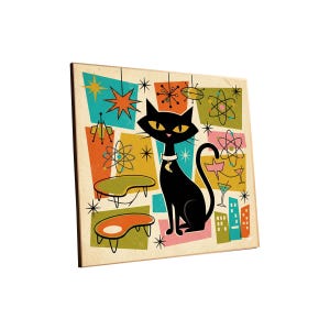 May include: A retro-style print featuring a black cat with yellow eyes, wearing a collar with a crescent moon. The background has colorful atomic age-inspired shapes and designs, including stars, atoms, and mid-century modern furniture.