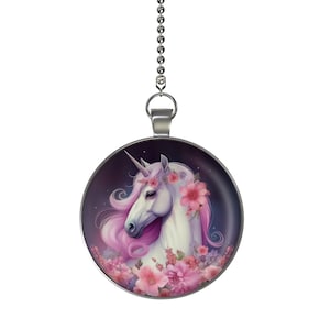 May include: A silver chain with a round pendant featuring a white unicorn with pink mane and tail surrounded by pink flowers on a dark purple background.