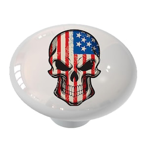 May include: A white ceramic knob with a skull design. The skull is painted with the American flag, with red and white stripes and blue stars.