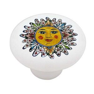 May include: Ceramic knob with a colorful sun face surrounded by flowers. The sun has a yellow face with red cheeks, blue eyes, and a red mouth. The flowers are in shades of pink, blue, green, and yellow.