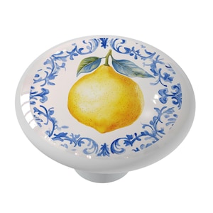 May include: A white ceramic knob with a blue and white floral design and a yellow lemon in the center.