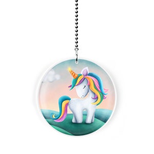 May include: A white unicorn with a rainbow mane and tail stands on a green grassy hill. The unicorn has a closed eye and a small orange horn. The background is a pastel pink and blue sky with a white cloud.
